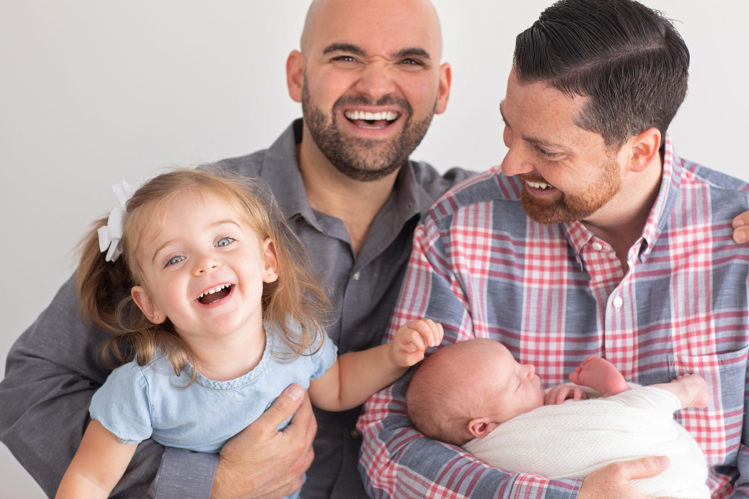Gay Family Laughing with Newborn in a photo studio