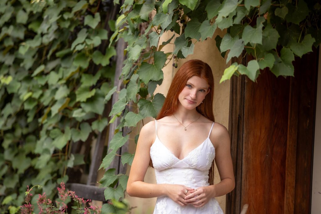 Stunning graduating high school senior in a white dress with red hair